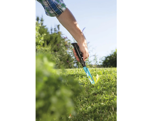 Zahradní scéna s rukou používající plečku v trávníku