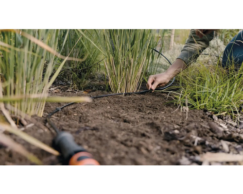 Osoba instaluje zavlažovací systém v zahradě.