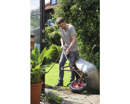 Muž čistí zahradním hadrem kolečko na zahradě.