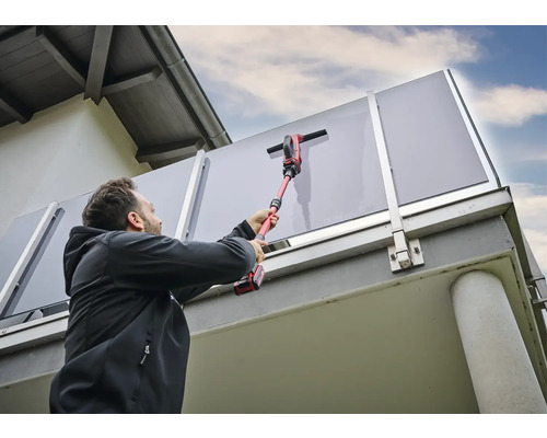 Muž čistí skleněné zábradlí akumulátorovou čističkou oken.