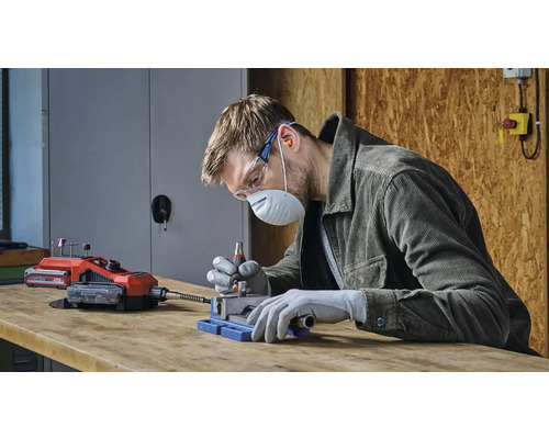 Muž pracuje s akumulátorovým multifunkčním nástrojem, chráněn bezpečnostním vybavením.