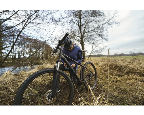 Muž opravuje své kolo v přírodě