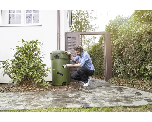 Muž opravuje sud na dešťovou vodu lepicí páskou na zahradě.