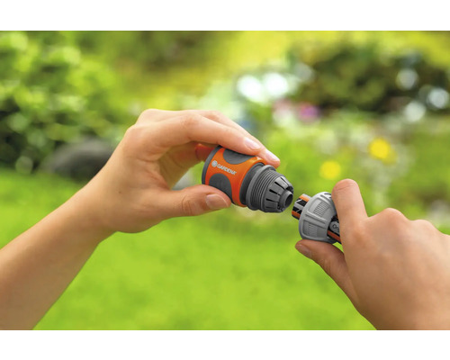 Osoba spojuje dva kusy hadice Gardena.