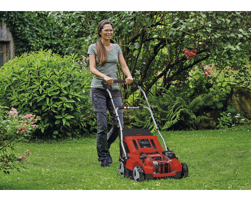 Žena obsluhuje červenou sekačku na trávu Einhell na zahradě.