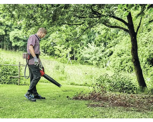 Osoba používá foukač listí pro zahradnické práce.