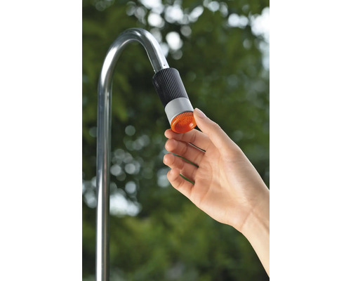 Ruka ovládá sprchovou hlavici kovové zahradní sprchy.