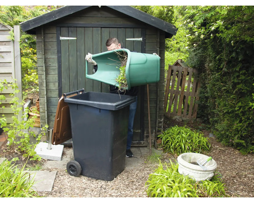 Muž vysypává zelený odpad do popelnice na zahradě