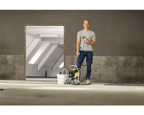 Muž s lakovací pistolí v prázdné místnosti