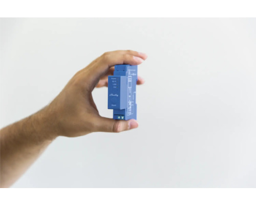 Ruka drží automatizační zařízení Shelly