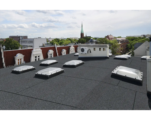 Střecha s bitumenovými pásy a střešními okny v městské scenérii