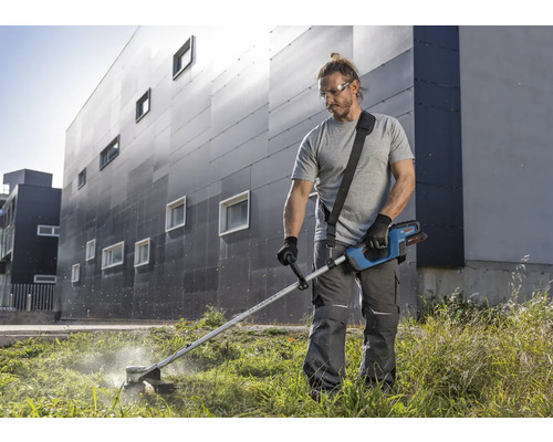 Muž stříhá trávu s akumulátorovým vyžínačem na zahradě