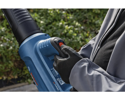 Osoba obsluhuje fukar na listí na zahradě.