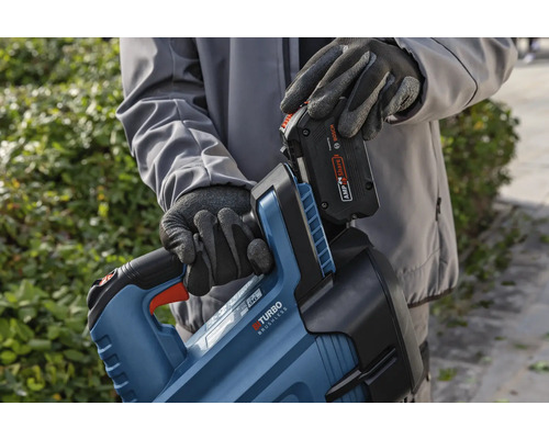 Osoba vkládá baterii do těla nůžek na živý plot.