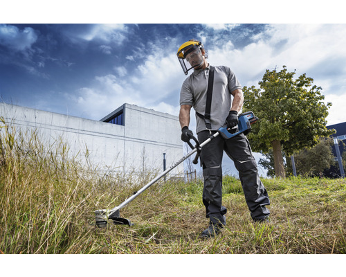 Osoba používá vyžínač s ochranným štítem na zahradě.