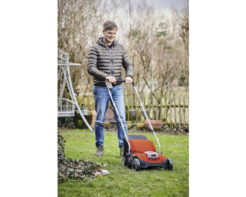 Muž používá provzdušňovač trávníku na zahradě.