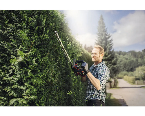 Muž stříhá živý plot pomocí nůžek na živý plot