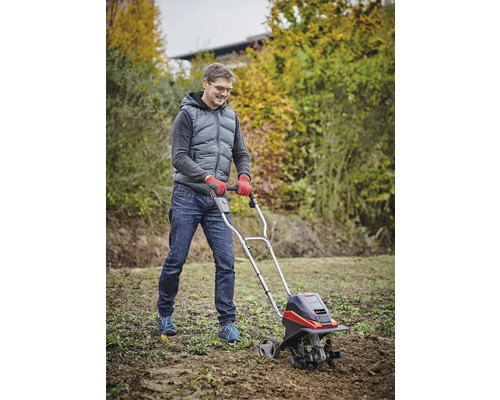 Muž pracuje se zahradní frézou pro zpracování půdy na zahradě.