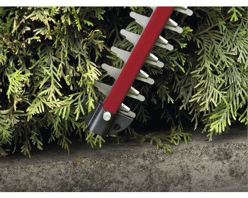 Detailní záběr nůžek na živý plot stříhajících živý plot