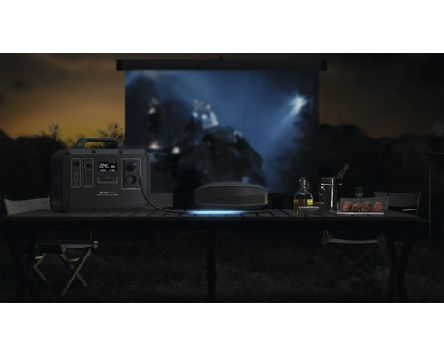 Venkovní scéna s napájecí stanicí Bluetti, projektorem a plátnem na stole