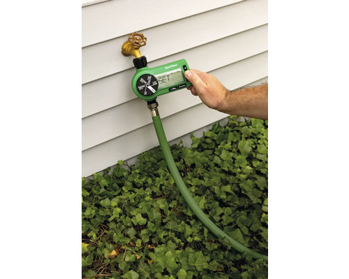 Zahradní zavlažovací počítač připojený k vodovodnímu kohoutku s hadicí, zavlažování nastavuje osoba.