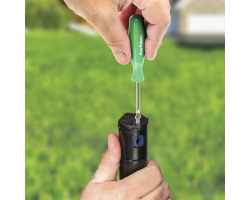 Osoba seřizuje zavlažovač pomocí šroubováku Rain Bird.