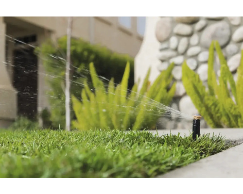 Zavlažovač trávníku zavlažuje trávník na zahradě