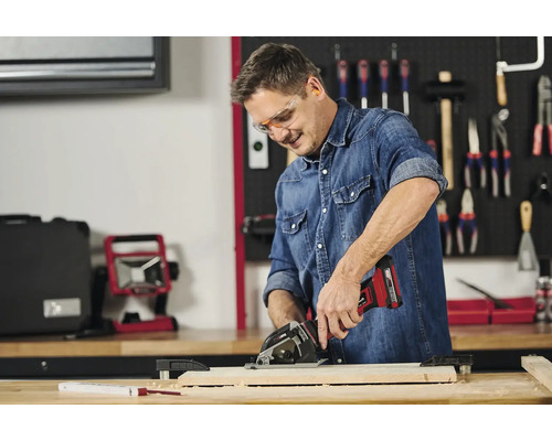 Muž pracuje s akumulátorovou ruční okružní pilou na kusu dřeva