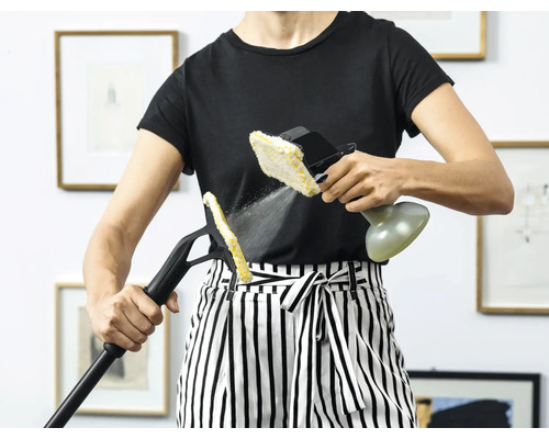 Osoba používá parní čistič s různými nástavci k čištění v interiéru.