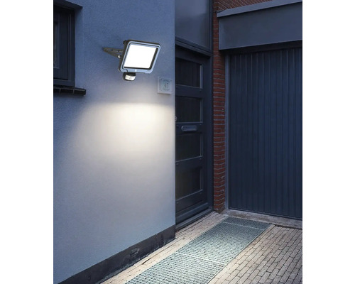 Venkovní fotografie stěny domu s namontovaným LED reflektorem s pohybovým senzorem