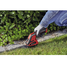 Logo Einhell. Osoba používá akumulátorové nůžky na trávu k zastřihávání okrajů trávníku.