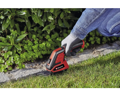 Logo Einhell. Osoba používá akumulátorové nůžky na trávu k zastřihávání okrajů trávníku.