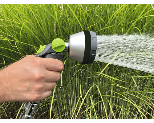 Zahradní hadice stříkací hlava v provozu před zelenou trávou