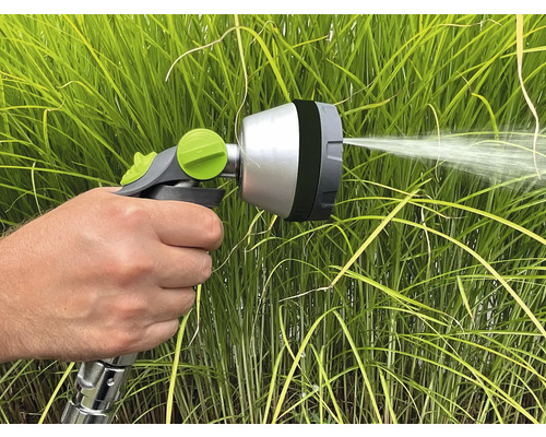 Ruka drží stříkací pistoli pro zalévání rostlin