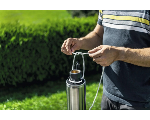 Muž upevňuje lano k ponornému tlakovému čerpadlu