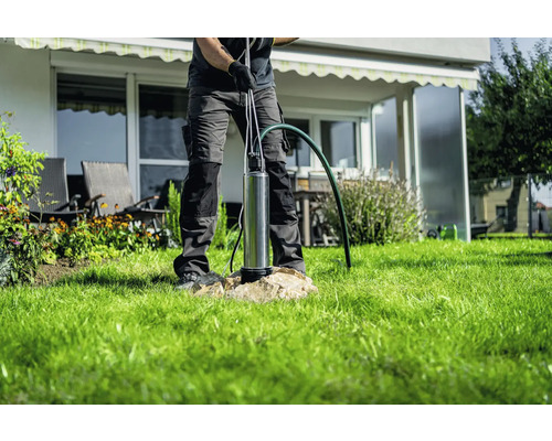 Muž instaluje hluboké studnové čerpadlo v zahradě.