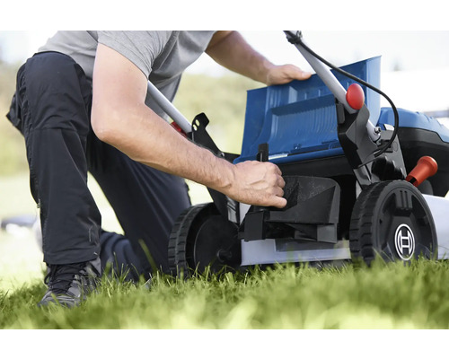 Osoba připravuje sekačku na trávu na zahradničení