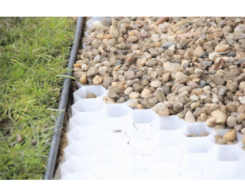 Detail záběru zatravňovací dlažby vyplněné štěrkem vedle trávníku