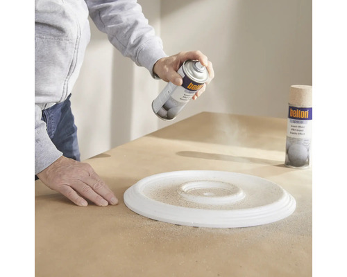 Osoba stříká barvu na rozetu pomocí spreje s žulovým efektem