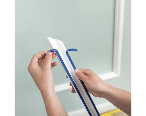 Osoba odstraňuje ochrannou fólii z ozdobné lišty pro dekoraci stěn.