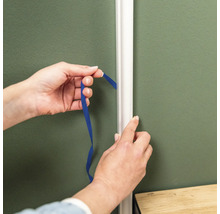 Ruce měří páskou vzdálenost k ozdobné liště