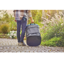 Osoba nese zahradní pytel Gardena na zahradě.