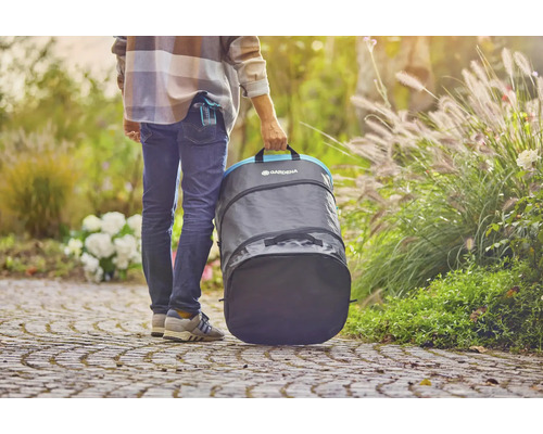 Osoba nese zahradní pytel Gardena na zahradě