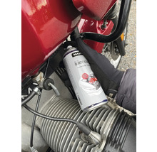 Osoba používá plechovku Auto Quick Start spreje na motorku.