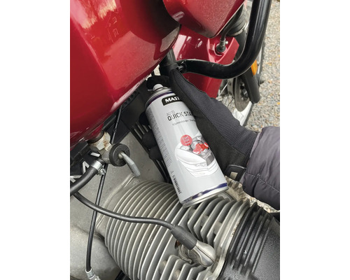 Osoba používá plechovku Auto Quick Start spreje na motorku.