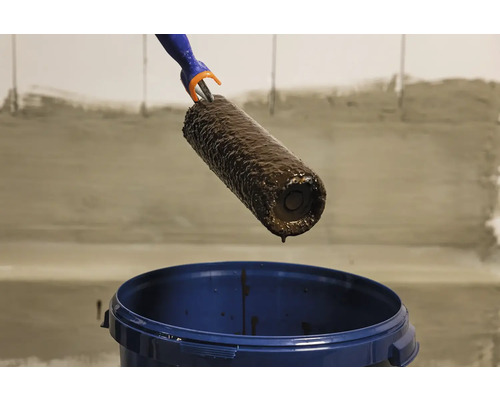 Váleček na malování nad kbelíkem s barvou.