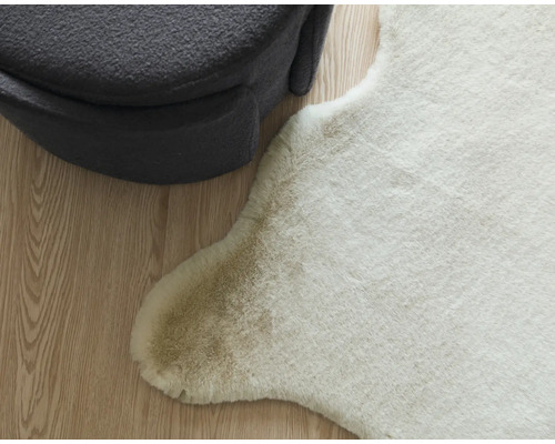 Dekorativní imitace zvířecí kůže vedle šedé taburetky na dřevěné podlaze.