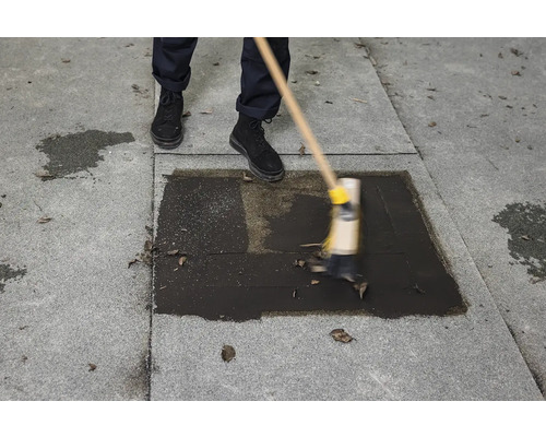 Osoba čistí šedý kamenný povrch koštětem