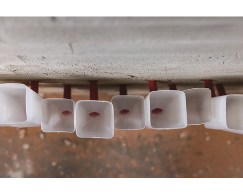 Řada ventilačních trubek na stropě s červeným držákem