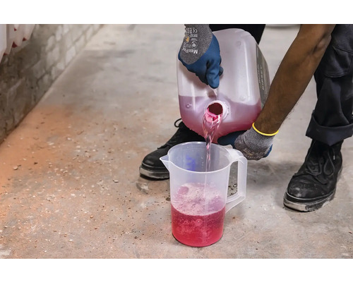 Osoba nalévá růžovou tekutinu z nádoby do odměrky.